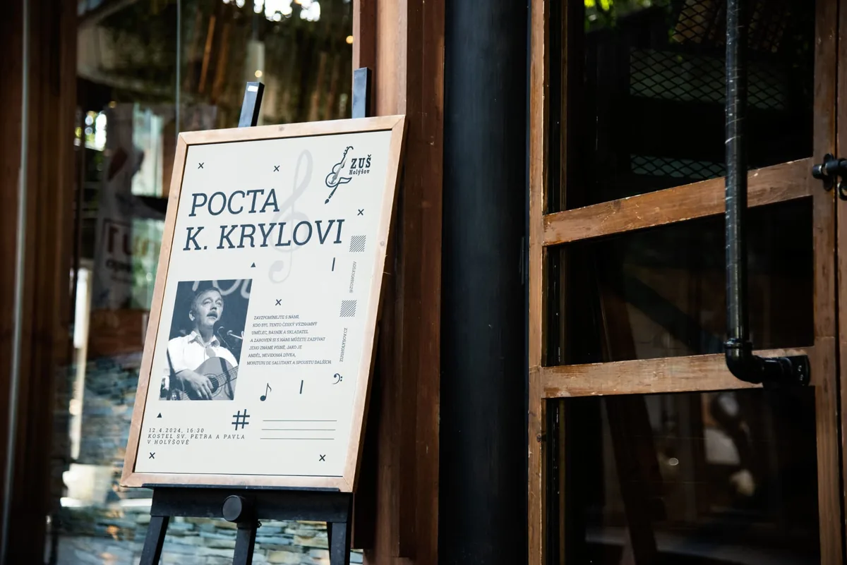 Plakát Pocta Krylovi na stojanu u vstupu do budovy